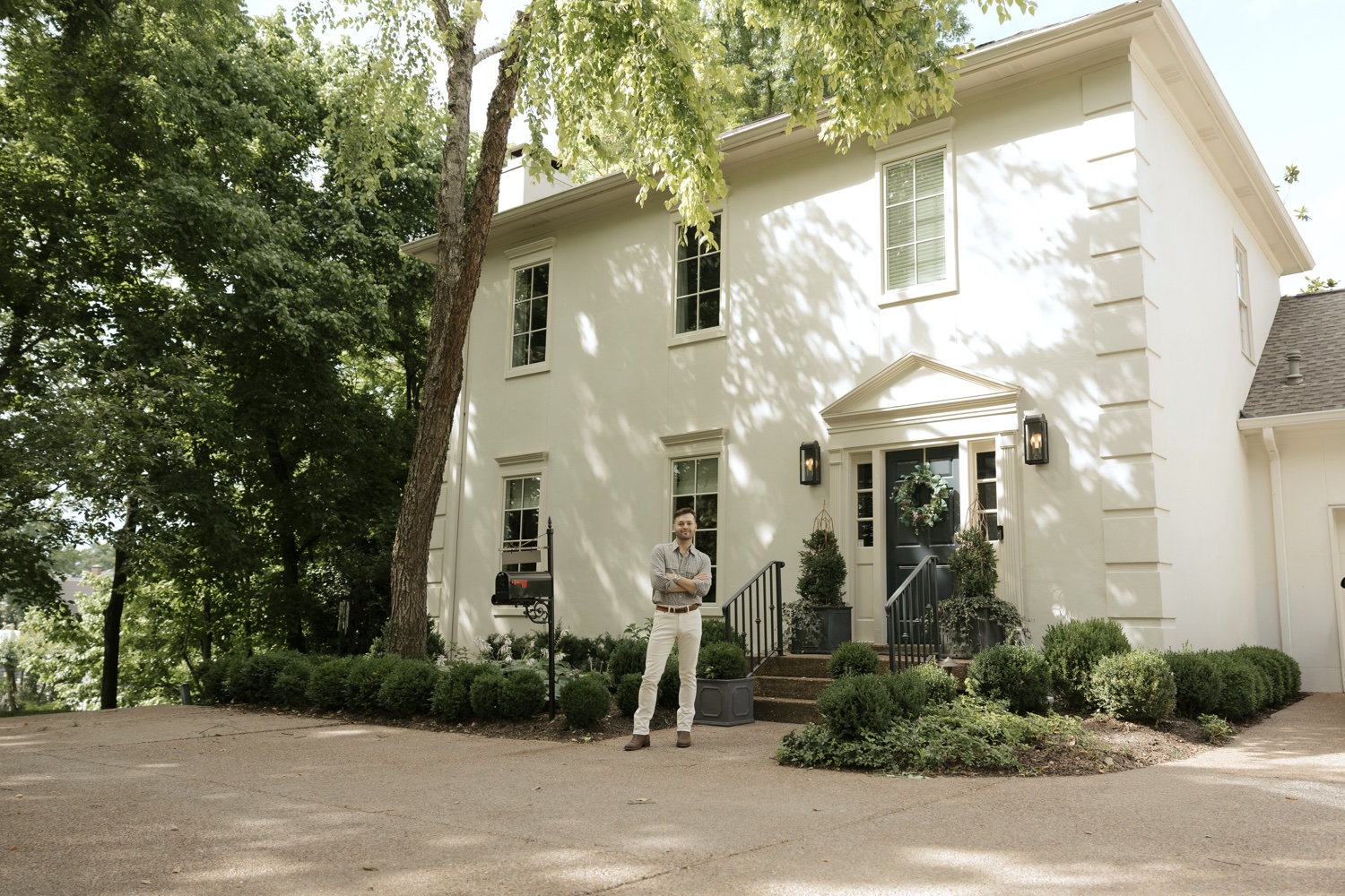 Colton Reid stands outside a Green Hills home framed by mature trees.