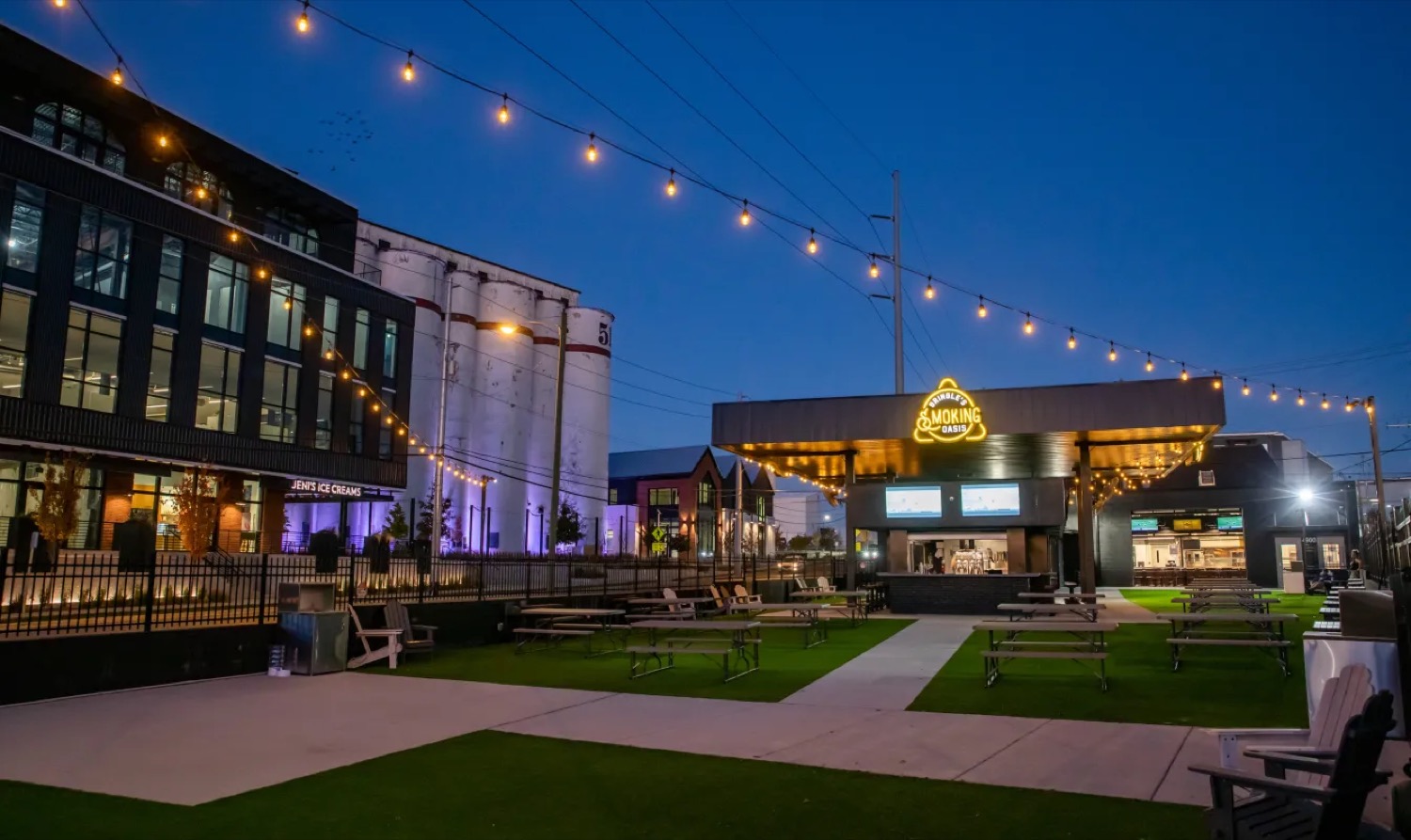 The Nations at dusk with silos, string lights, outdoor seating, and local businesses in Nashville.